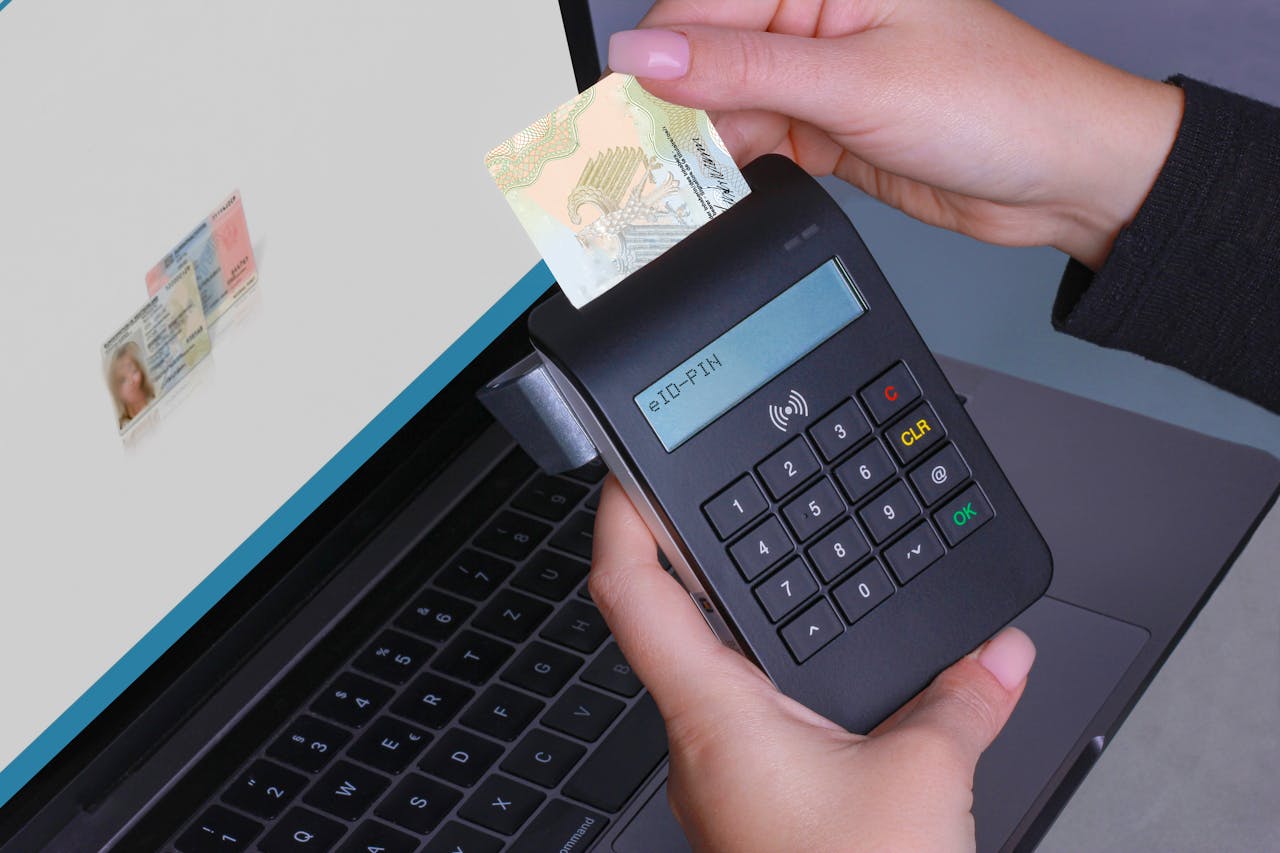 Person using contactless device for ID payment verification on a laptop.