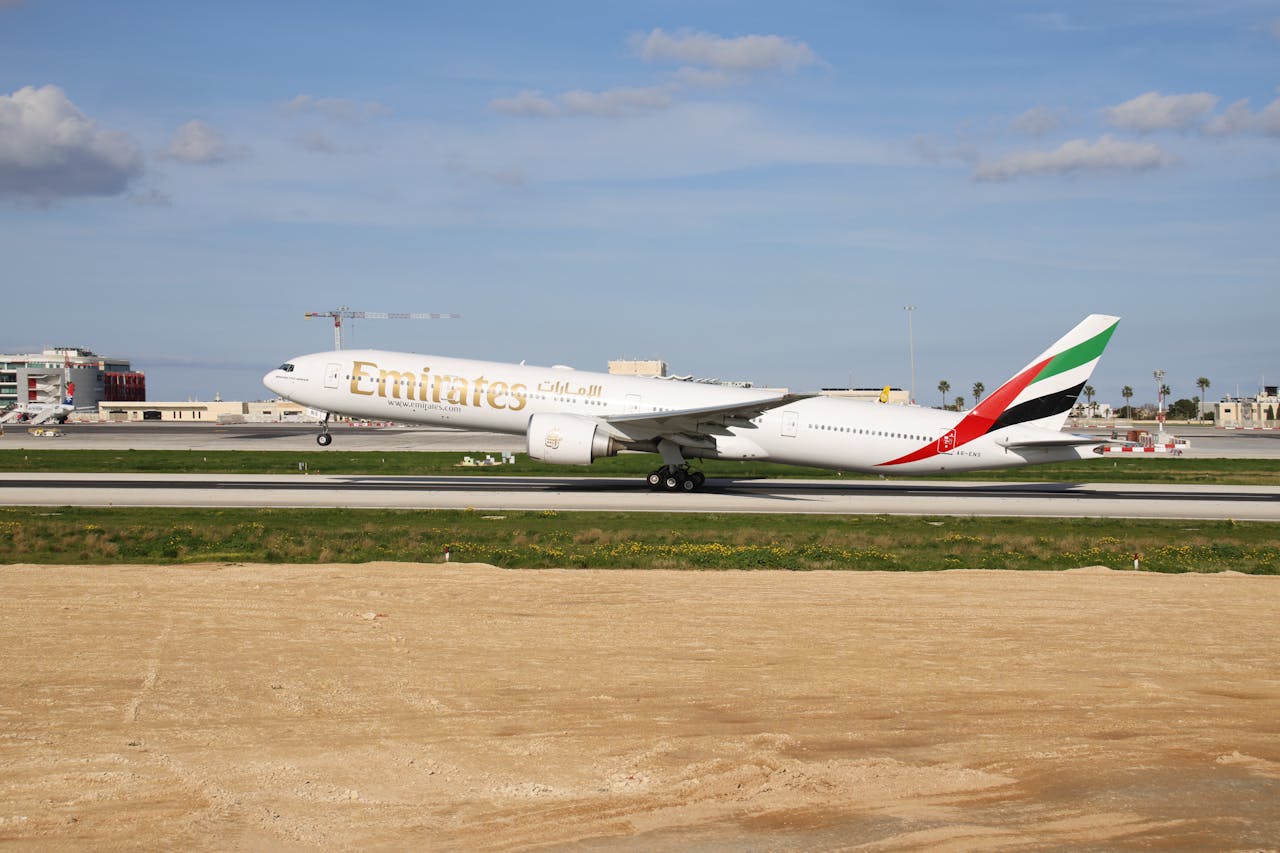 Emirates Boeing 777 aircraft on runway under clear blue sky.