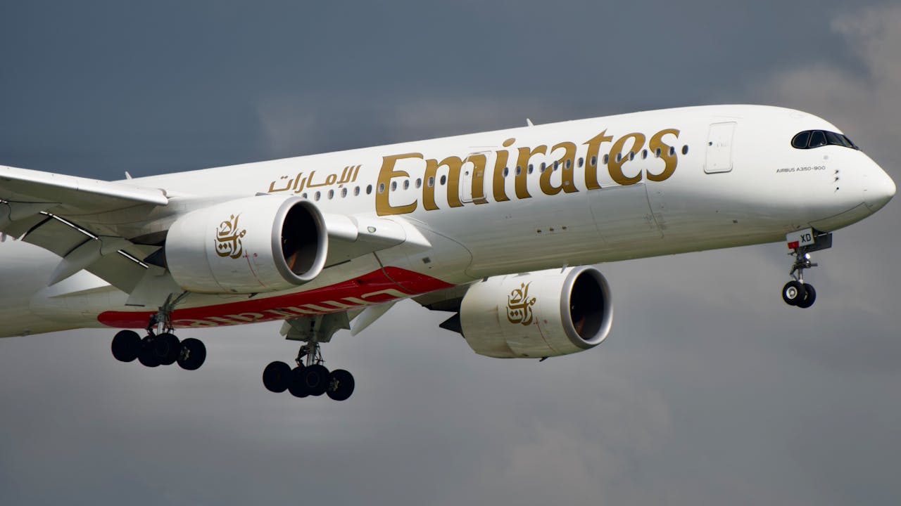 A striking image of an Emirates Airbus A350 soaring through the sky with landing gear down.