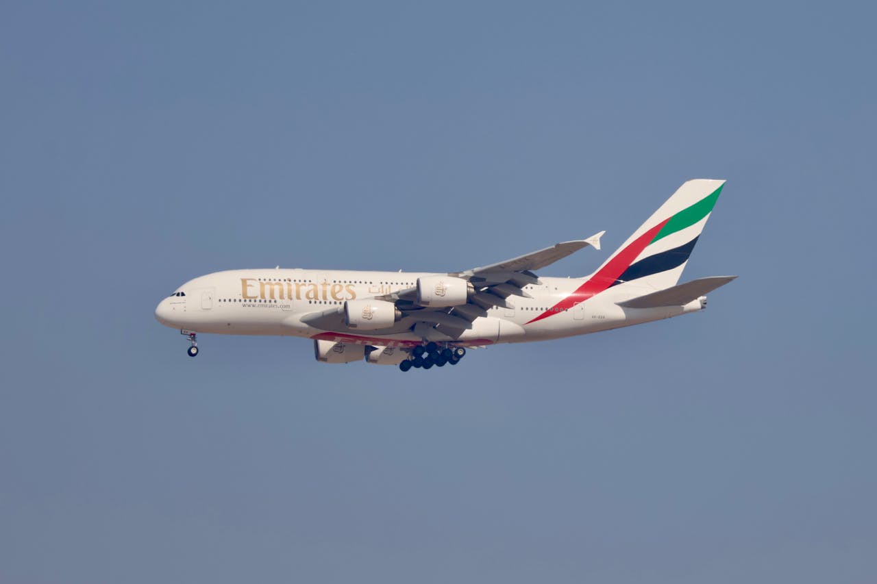 Emirates Airbus A380 flying against clear blue sky, showcasing aviation elegance.
